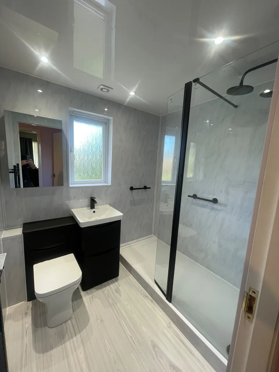 Black vanity and glass shower screen with pale walls