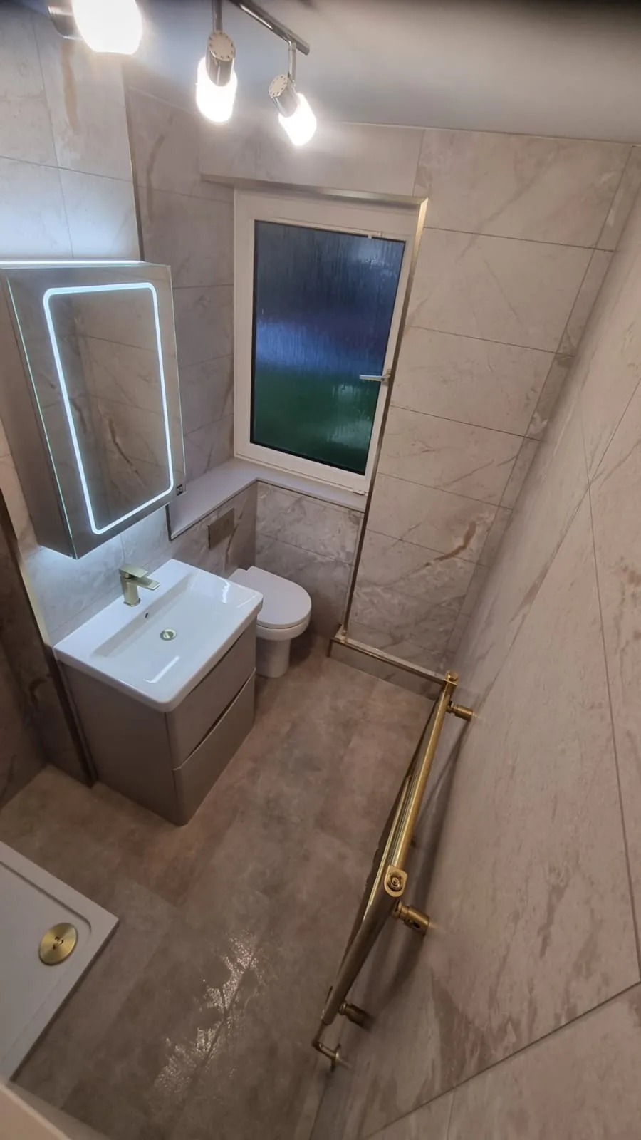 Wall-hung vanity beneath an illuminated mirror